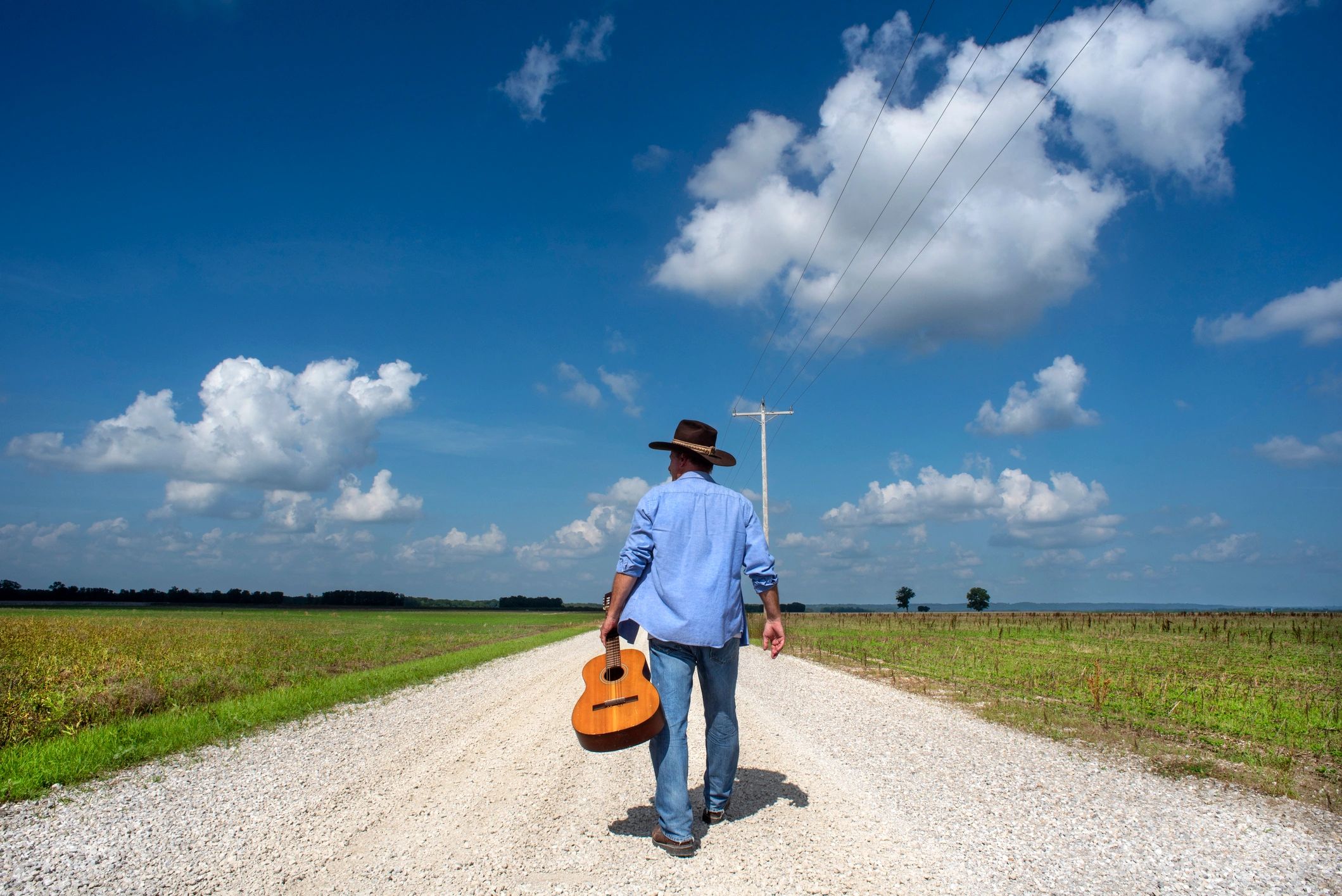 Musician walking down a country road with guitar