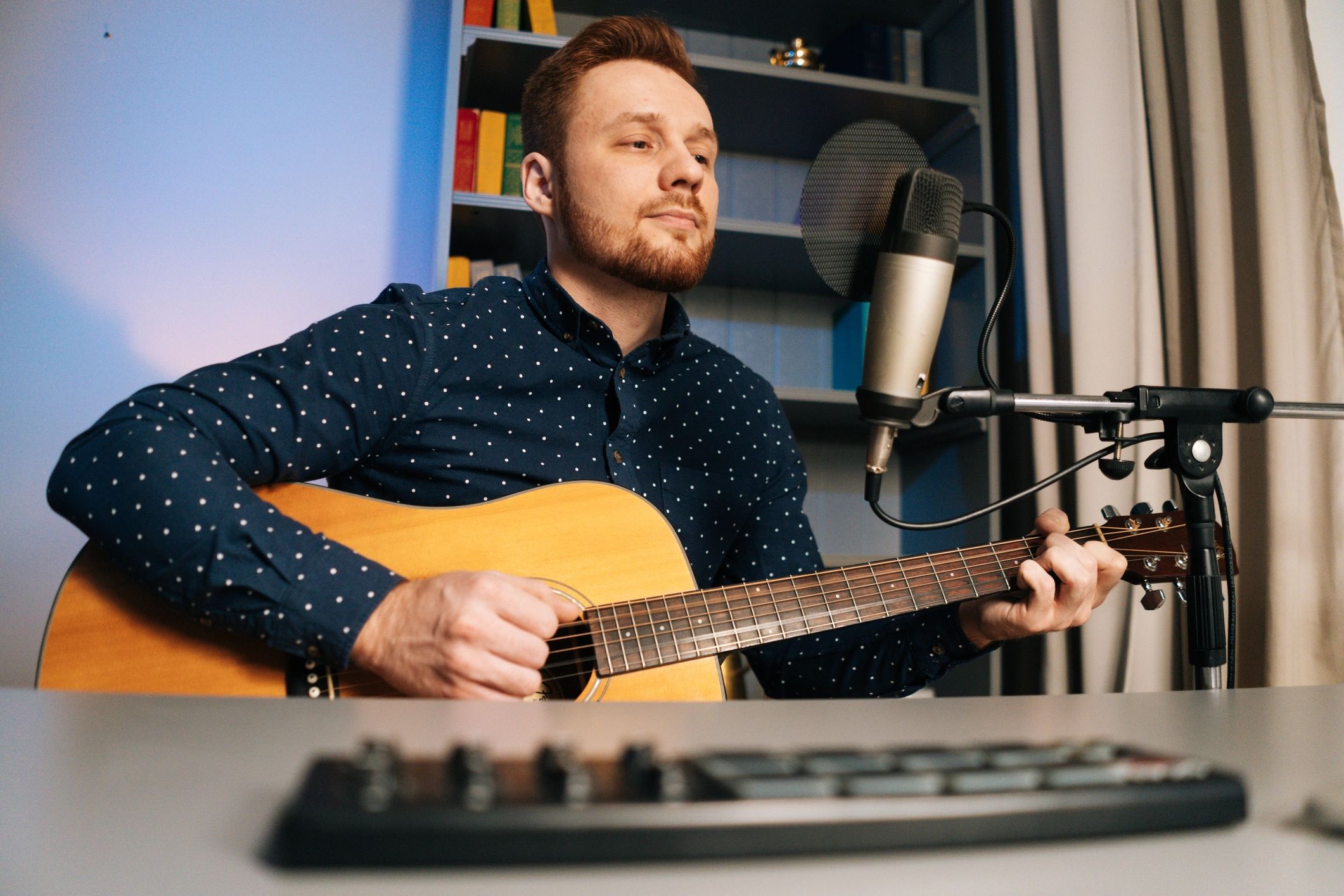 Musician recording acoustic guitar and vocals in a home studio