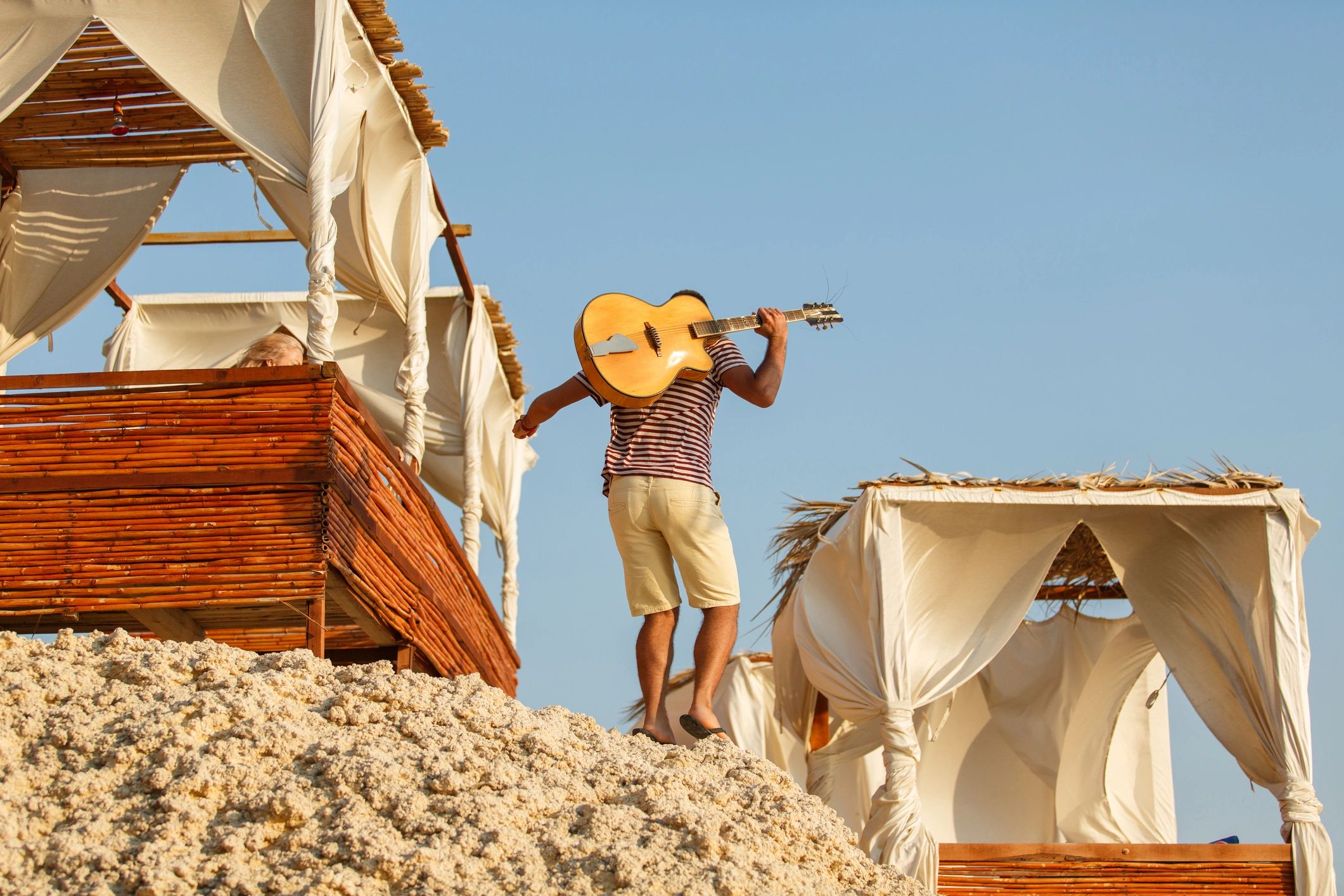 Musician carrying acoustic guitar outdoors